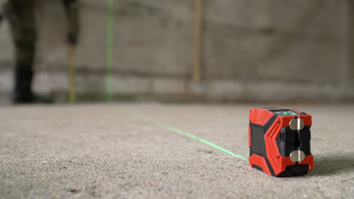 Laser level and tape measure on a bare concrete floor during a material takeoff